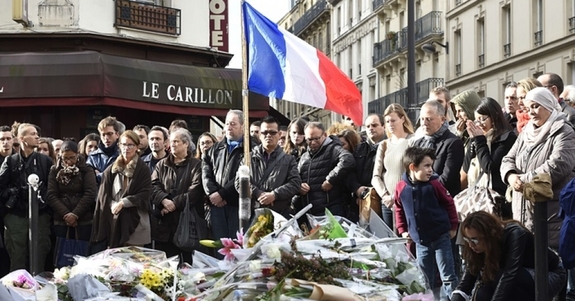 People observe a minute’s silence at the Le Carillon cafe, where 15 people were killed. (Photo: Eric Feferberg/AFP/Getty)