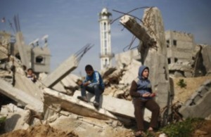 Palestinian boys attend Friday prayers as they sit at the remains of a house that witnesses said was destroyed by Israeli shelling during a 50-day war last summer, in the Shejaia neighbourhood east of Gaza City January 23, 2015.
