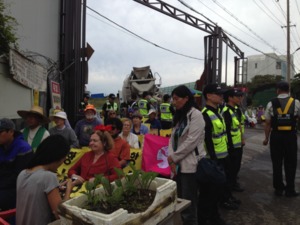 Photo with Ann Wright’s camera.  Nobel Peace laureate Mairead Maguire, Ann Wright, Catholic sisters and other Gangjeong activists after having been lifted up and carried in chairs out of the road to allow steady stream of concrete trucks to enter the nava