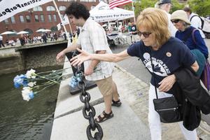 Linda Hickey and others tossed carnations representing service members killed in war during a Veterans for Peace ceremony on Memorial Day